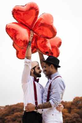 two men holding red heart balloons